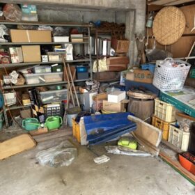 片付け前のガレージの写真。床の端や棚に様々な物が所狭しと置かれている。