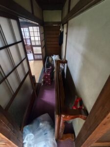 片付け前の廊下。座卓やゴミ袋が置かれており動線が狭くなっている。