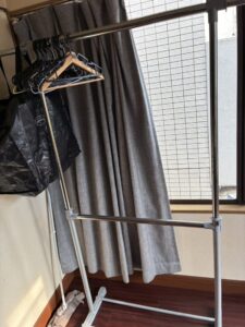 作業前の寝室左側。窓にはカーテンがかかっており、窓の前にはハンガーラックとハンガーが置かれている。