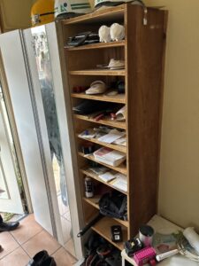 作業前の玄関。背の高い靴箱に靴が何足も入っており、靴箱の上にはヘルメットが3点置かれている。