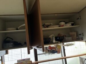 作業前のキッチン。吊戸棚の中にフライパンなどの調理器具、おわんなどの食器類が入っている。