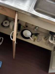 作業前のキッチン。シンク下の戸棚の中にフライパンや食器類が置かれている。