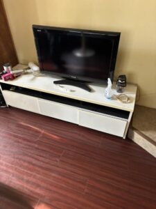 作業前のリビング。テレビ台とその上に置かれたテレビと生活雑貨。