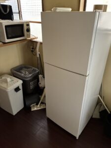 作業前のミニキッチン。2ドア冷蔵庫や電子レンジ、ゴミ箱が2つ置かれている。